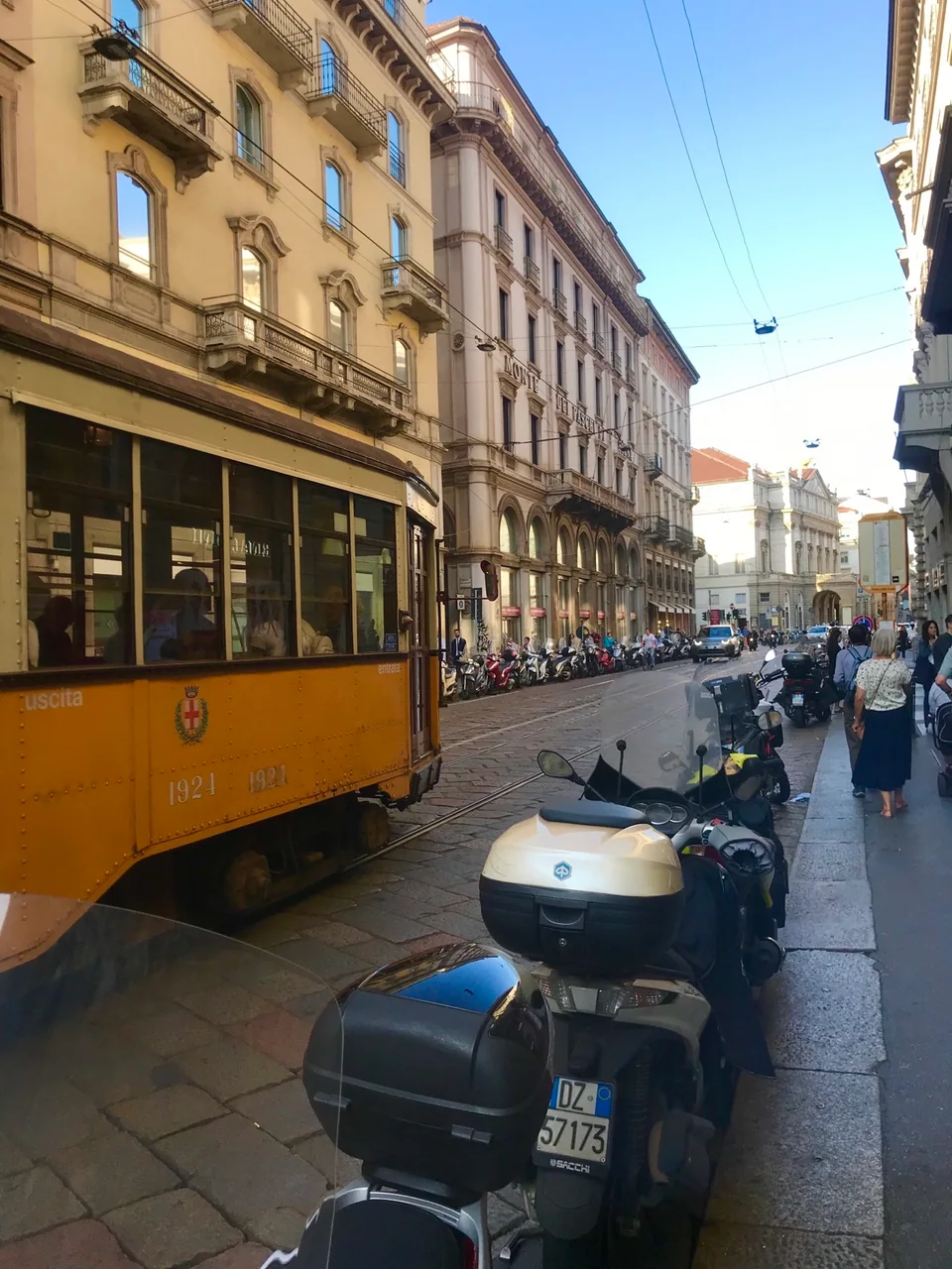 A yellow tram on a sunlit street in Milan